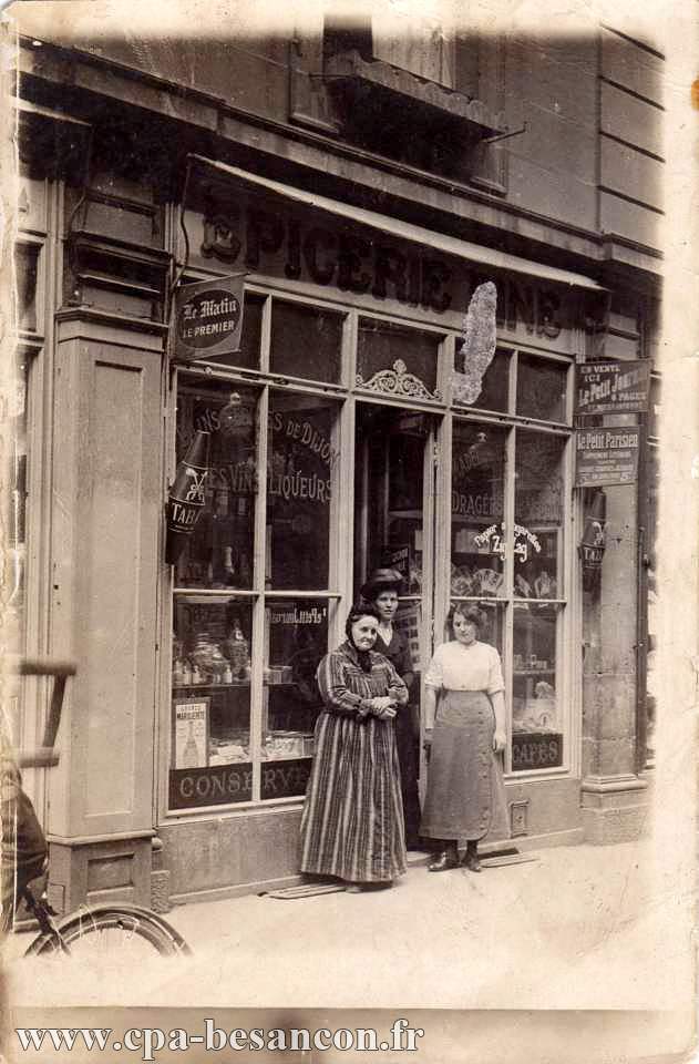 Trois femmes posant devant une épicerie fine (vente de tabacs, vins, liqueurs, dragées, journaux...)